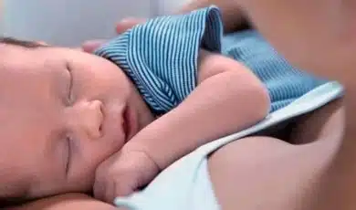 תינוק ישן על הידיים של אמא שלו