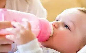 תינוק עם בקבוק חלב בפיו