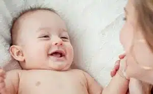 אמא רוכנת מעל תינוק מחייך