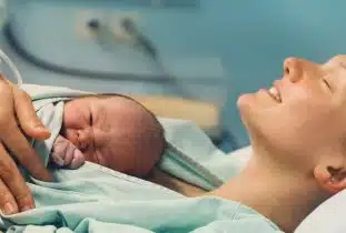 אישה לאחר לידה עם התינוק עליה