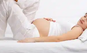 אישה בהריון מחזיקה את הבטן ונחה על הספה
