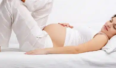 אישה בהריון מחזיקה את הבטן ונחה על הספה