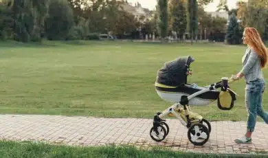 אמא מטיילת עם עגלת תינוק בפארק