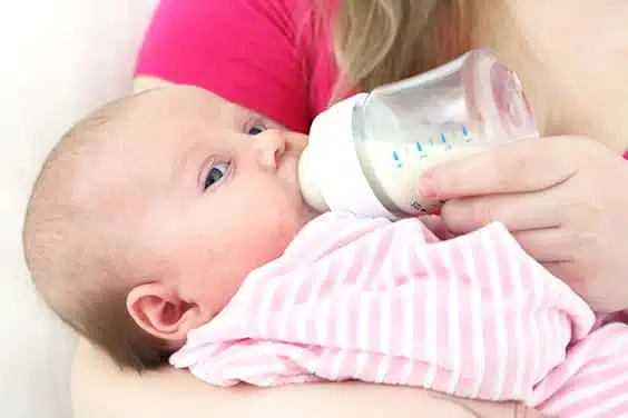 אמא יושבת מאכילה תינוק בבקבוק חלב