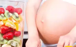 אישה בהריון חותכת פירות ולידה כלי עם פירות