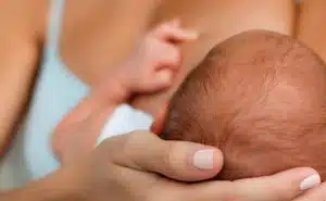 אמא מחזיקה את ראשו של תינוקה היונק