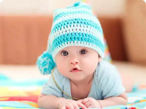 תינוק עם כובע כחול סרוג שוכב 