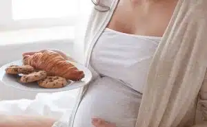 אישה בהריון מחזיקה צלחת עם קוראסון ועוגיות