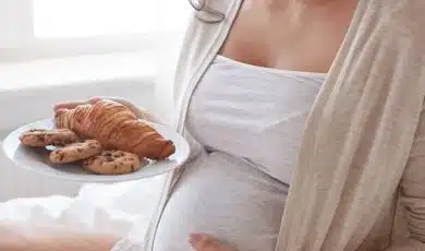 אישה בהריון מחזיקה צלחת עם קוראסון ועוגיות
