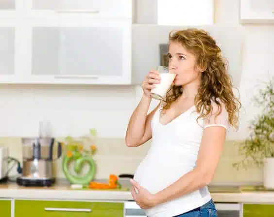 אשה בהריון מחזיקה כוס חלב