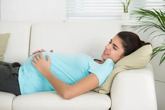 תמונה של אישה בהריון שוכבת על הספה עם כאבים
