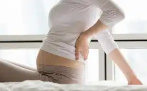 אישה בהריון מחזיקה את הגב התחתון