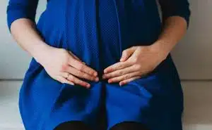 אישה בהריון יושבת ומחזיקה את הבטן