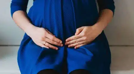 אישה בהריון יושבת ומחזיקה את הבטן