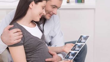 זוג צעיר מעיין בתוצאות בדיקת אולטרסאונד עם תמונת עובר