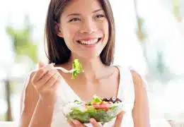 אישה צעירה מחייכת אוכלת סלט
