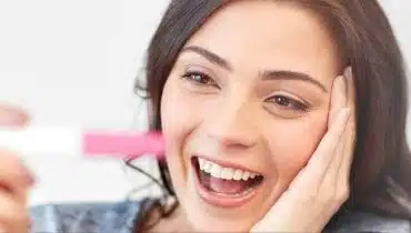 אישה מחייכת מחזיקה בדיקת הריון