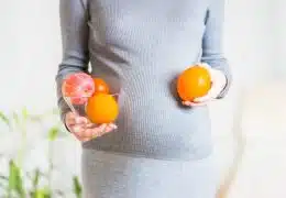 אישה בהריון מחזיקה תפוזים