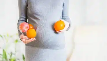 אישה בהריון מחזיקה תפוזים