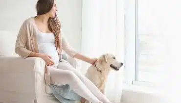 אישה בהריון עם הכלב שלה בבית