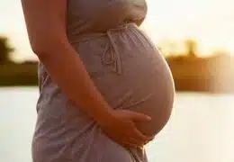 אישה בהריון בשקיעה מחזיקה את הבטן