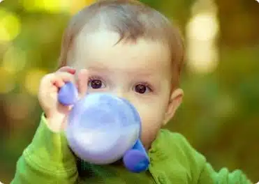 תינוק שותה חלב מכוס