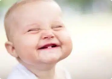 תינוק מחייך עם שתי שיניים תחתונות בפה