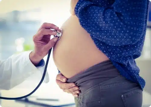 רופא בודק עם סטטוסקופ בטן של אישה בהריון