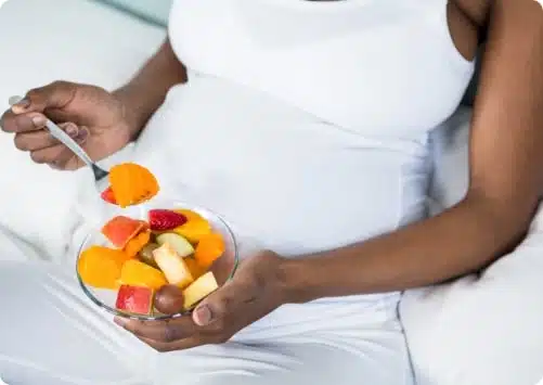 אישה צעירה בהריון אוכלת סלט פירות