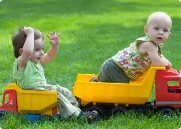 שני תינוקות משחקים יחד בדשא