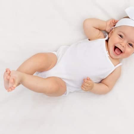תינוקת מחייכת לבושה בבגדים לבנים
